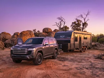 A 4WD and JB caravan together at a remote camp, late afternoon light, dust still settling behind the rig